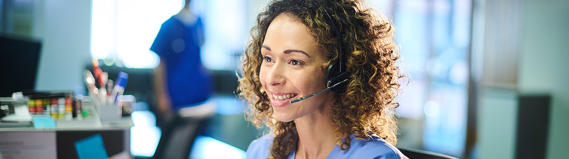 Female nurse on phone headset in front of computer