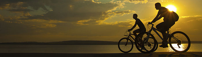 two people riding bikes into the sunset