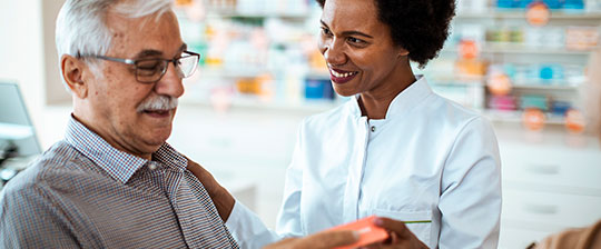 Pharmacist discusses medication with senior male